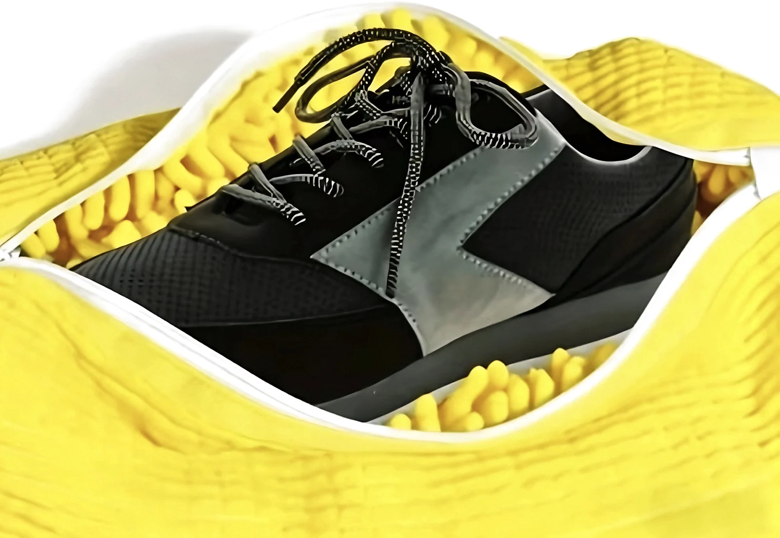 A black sneaker resting on yellow fibers inside the open bag